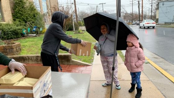 BGCM Staff handing out grab-n-go meals int the rain
